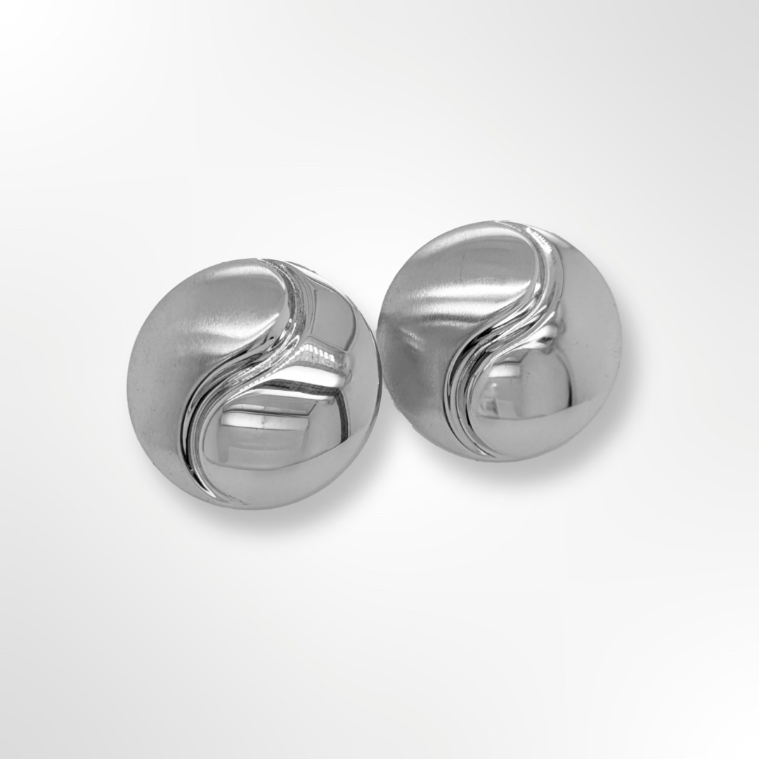 A pair of sterling silver round clip-on earrings featuring a curved engraved detail